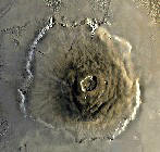 гора Олимп (Olympus Mons) - Самый высокий пик на Марсе и самый большой вулкан Солнечной системы. Возвышается на 27 км выше опорного уровня (определенного по измерениям атмосферного давления). Этот гигантский щитовой вулкан, имеющий в поперечнике около 700 км, подобен вулканам на Земле, но его объем по крайней мере в пятьдесят раз превышает самый близкий земной эквивалент. Кальдера имеет диаметр около 90 км, причем гора окружена откосом высотой по крайней мере 4 км. Более старые вулканические породы, сглаженные и разрушенные ветром, окружают главный пик, образуя область ореала. Гора Олимп расположена в северо-западной части гор Фарсида и ранее называлась 'Олимпийские снега', поскольку облака, постоянно клубящиеся над этой областью, для земных наблюдателей выглядели как светлое пятно.