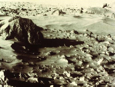 На фотографии, полученной 'Викингом-1' в месте его посадки в районе равнины Хриса, видны дюны и неровные каменные глыбы.